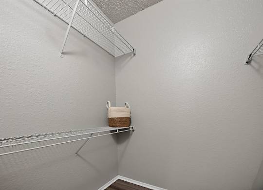 A small closet with a shelf and a basket on it.