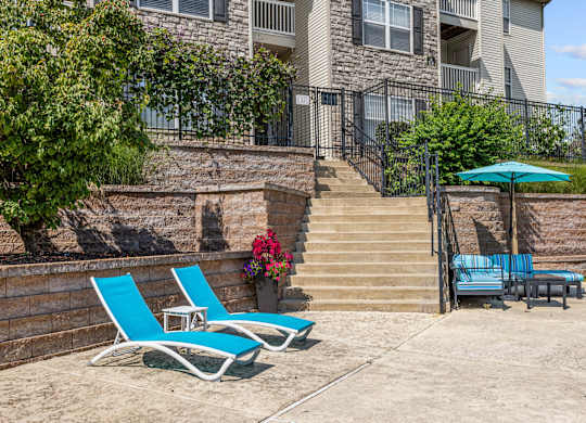 Two blue chairs and lounge area with umbrella on the sundeck.