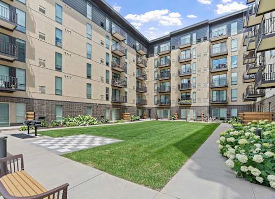 Apartment complex with a green lawn and a bench.