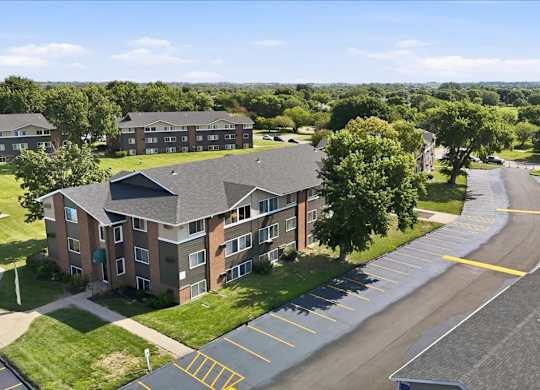 A large apartment complex with a parking lot in front.