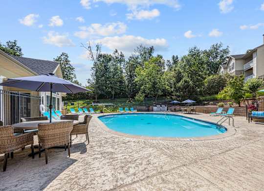 A large outdoor swimming pool surrounded by lounge chairs and umbrellas.