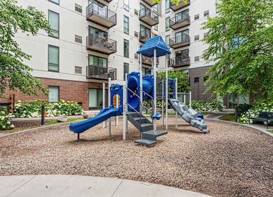 A playground with a blue slide and a white railing.