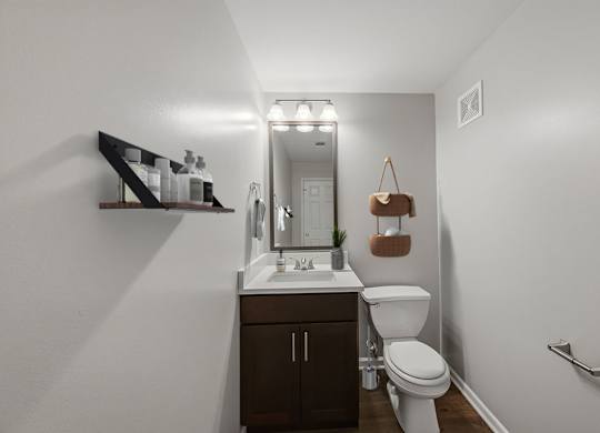 A bathroom with a toilet, sink, and mirror.