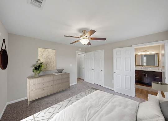 A bedroom with a white bed and a ceiling fan.