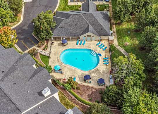 A swimming pool surrounded by trees and a house.