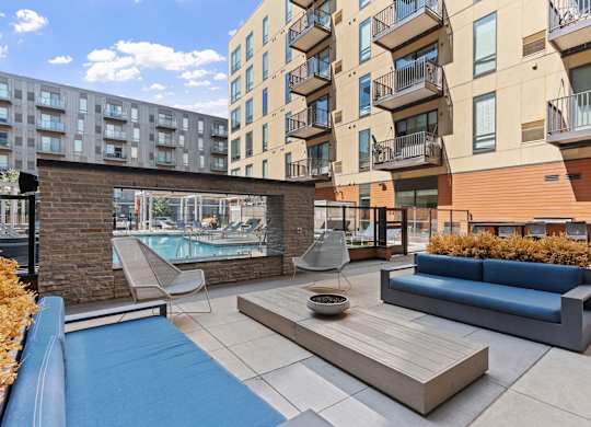 A modern outdoor seating area with a pool and a brick wall.