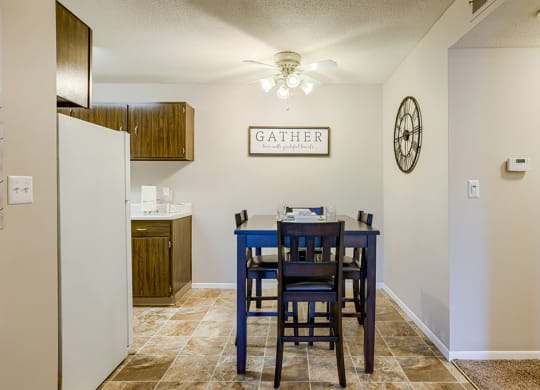 a dining table with blue chairs in a kitchen with a refrigerator