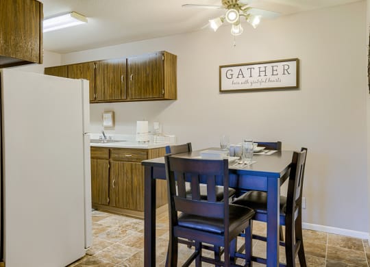 a dining area with a table and chairs and a kitchen with a refrigerator