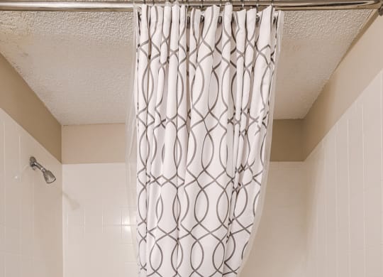 a white bathroom with a shower curtain and a tub
