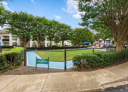 A dog park is surrounded by a black fence and has a sign that says Dog Park.