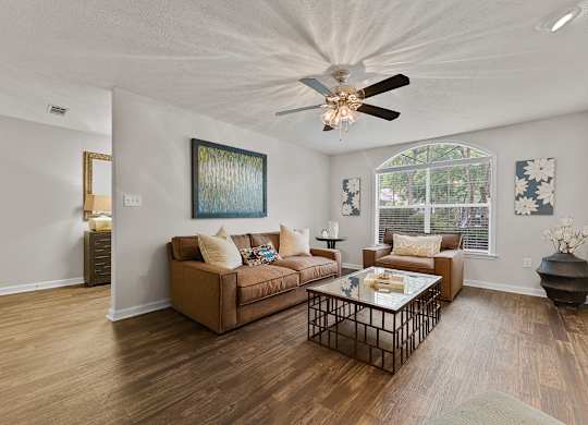 A living room with a brown couch and a painting on the wall.