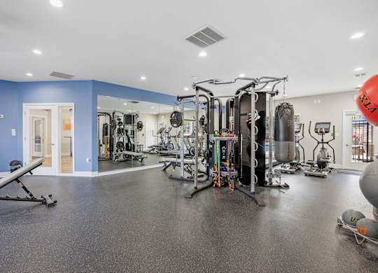 A gym with a variety of equipment including a leg press machine, a squat rack, and a bench press.