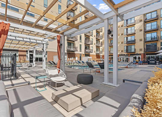 A patio with a white pergola and orange curtains.