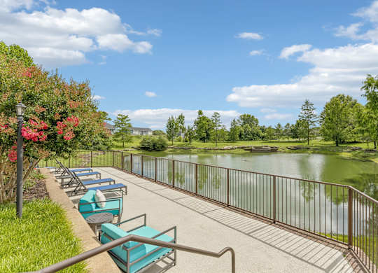 A row of lawn chairs are lined up on a concrete patio next to a metal railing.