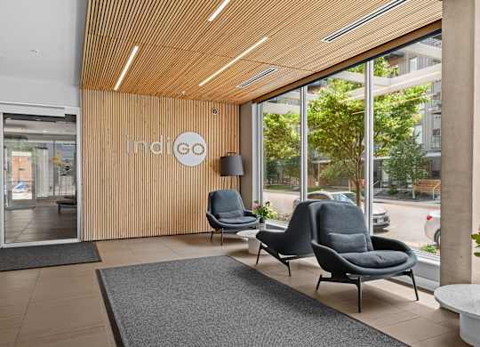 Indigo logo on a wooden wall above a grey chair.