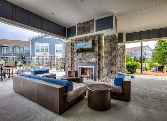A modern outdoor living space with a stone fireplace and seating area.