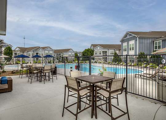 A poolside table and chairs are set up on a patio.