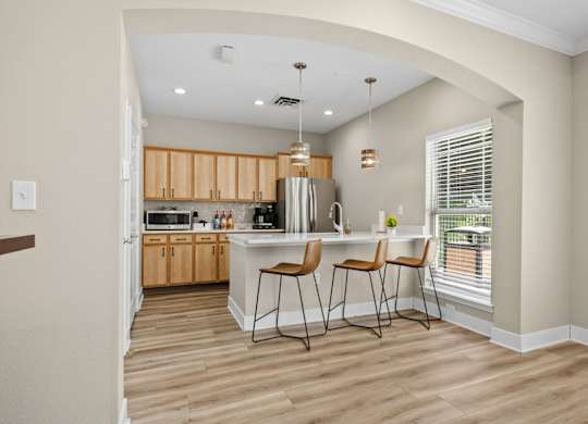 A kitchen with wooden floors and a bar area with two chairs.