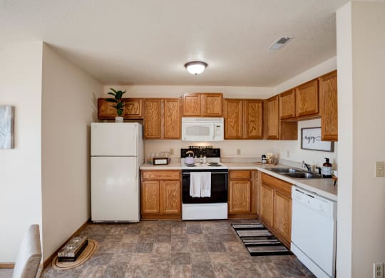 Spacious Kitchen With Tile-Style Flooring, Oak Cabinets & White Appliances
