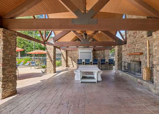 A patio with a white table and chairs under a wooden roof.