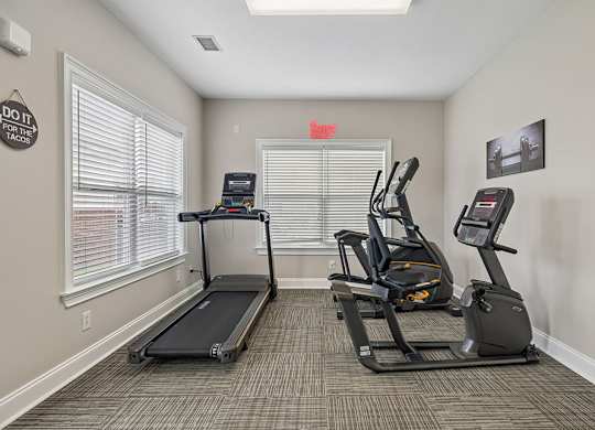 A gym room with treadmills and elliptical machines.