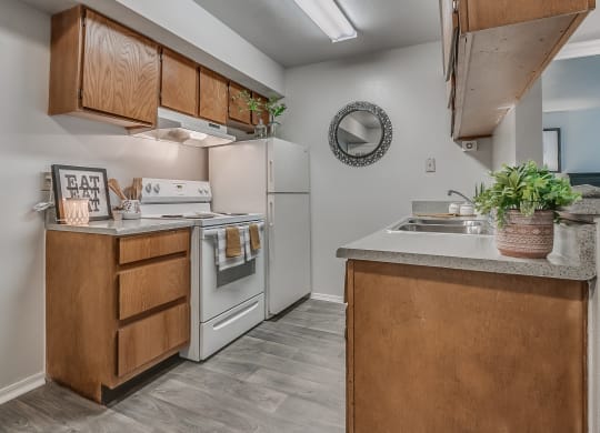 Galley Kitchen With White Appliances & Wood-Style Flooring