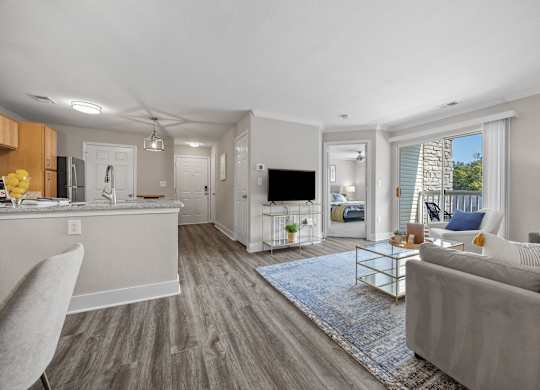 A modern living room with a grey couch and a kitchen area in the background.