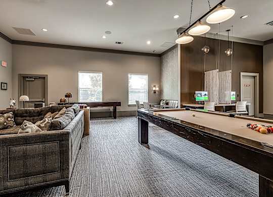 A spacious living room with a pool table and a couch.