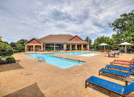 A large outdoor swimming pool with a red building in the background.