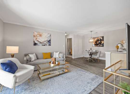 A living room with a white chair and a blue rug.