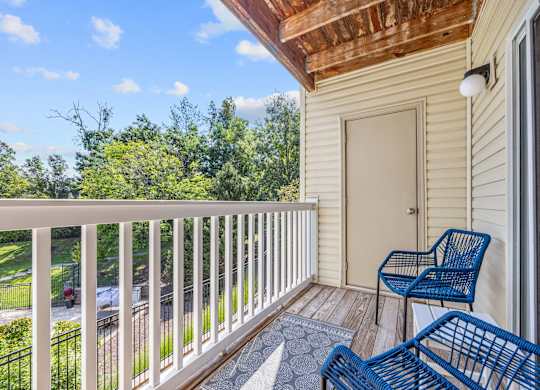 A balcony with a blue chair and a white railing.