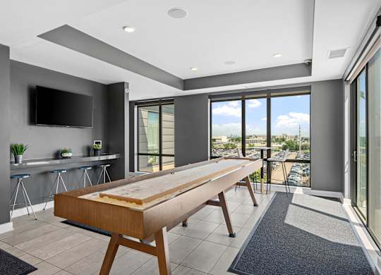 A modern kitchen with a long wooden table and a flat screen TV mounted on the wall.