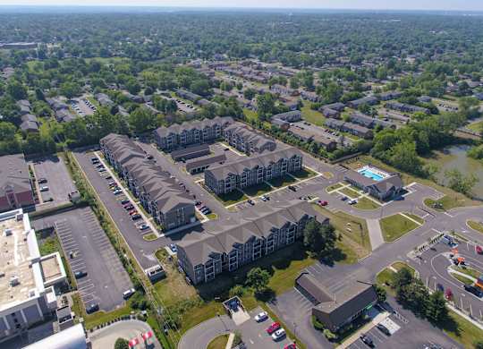 An aerial view of a residential area with apartment buildings and a parking lot.