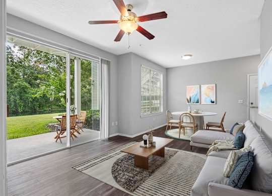 A living room with a ceiling fan and sliding glass doors.