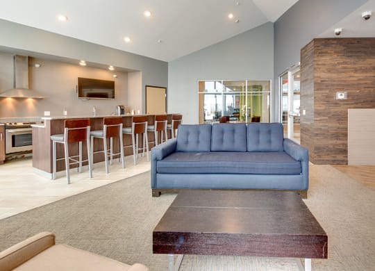 a living room with a blue couch in front of a bar