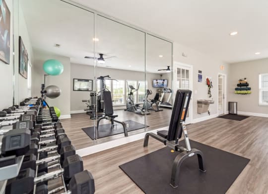 a gym with cardio equipment and mirrors at the bradley braddock road station apartments