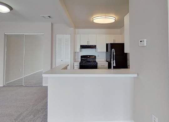 A kitchen area with a black fridge and white countertop.