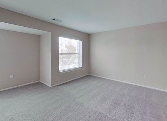 A room with a large window and a carpeted floor.