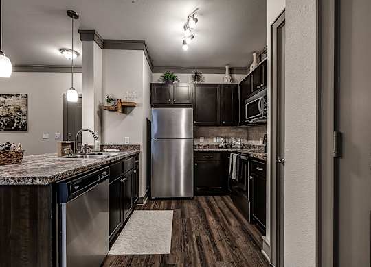 A kitchen with a stainless steel refrigerator and wooden floors.