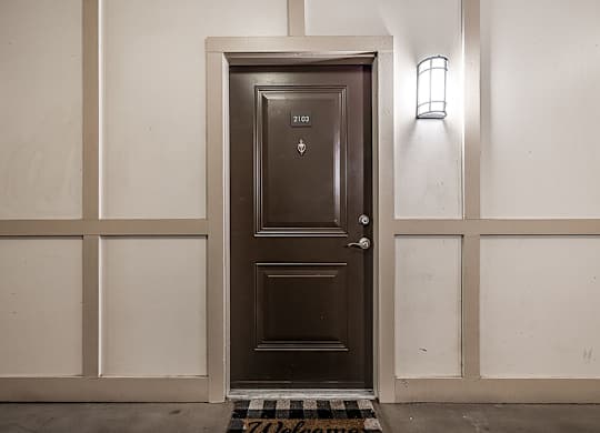 A brown door with a welcome mat in front of it.