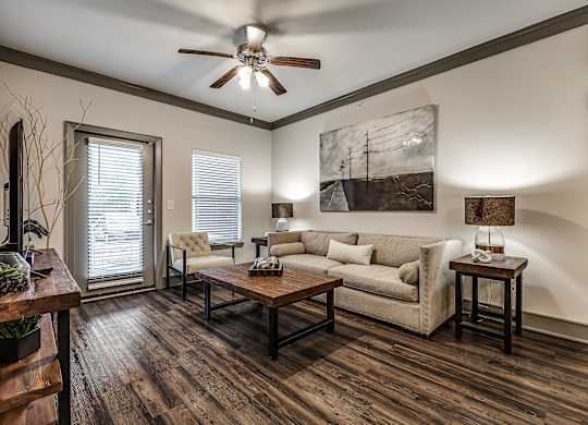 A living room with a couch, a chair, a coffee table, and a painting on the wall.