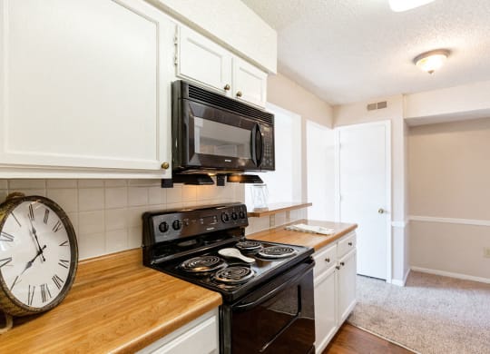 Classic Kitchen with White Cabinets, Black Appliances and Butcher Block Counters