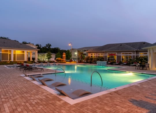 Zero-Entry Pool Lit Up At Night With Lounge Chairs