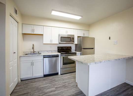A kitchen with white cabinets and a marble countertop.