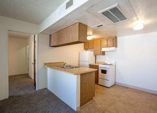 A kitchen with a white stove and wooden cabinets.
