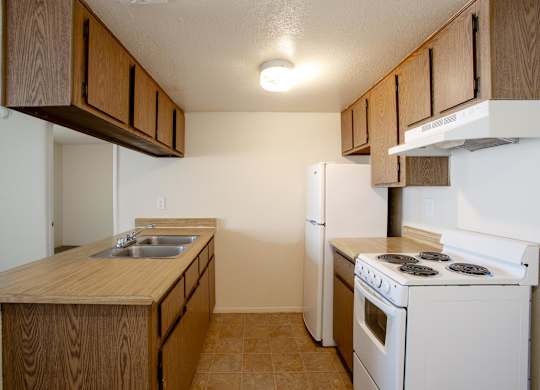 A kitchen with a white stove and wooden cabinets.