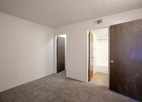 A room with a carpeted floor and two doors, one of which is open.