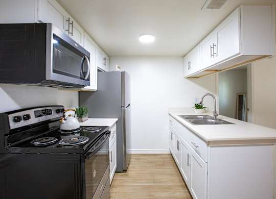 A kitchen with black and white appliances and wooden floors.