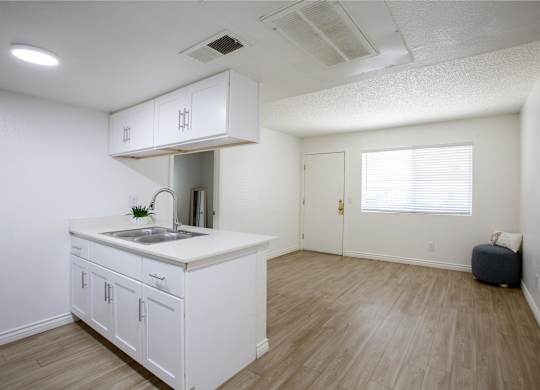 A kitchen with white cabinets and a wooden floor.