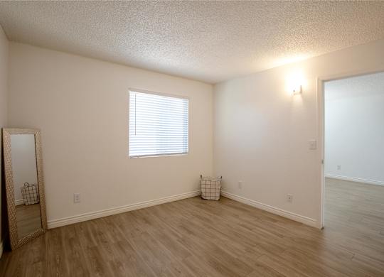 A room with a window and a wooden floor.